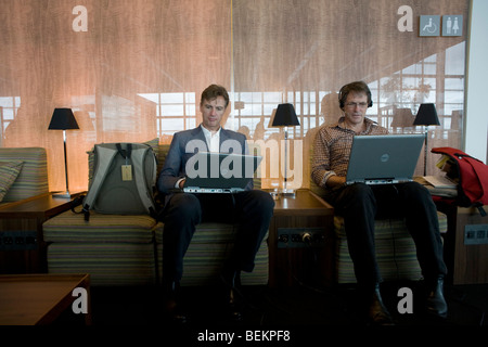 In the British Airways Galleries First lounge at Heathrow Airport's Terminal 5, two businessmen sit with identical Dell laptops. Stock Photo