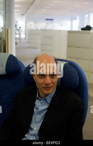 Writer Alain de Botton's sits in an airline seat at the British Airways' corporate headquarters at Waterside. Stock Photo