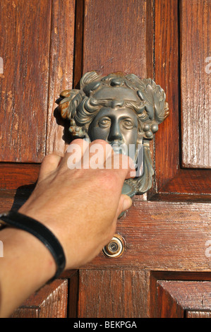 A closeup of a hand knocking on a wooden door. Stock Photo
