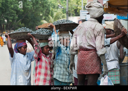 Indian women carrying stones in metal bowls on their heads, to make concrete on an India building site. Andhra Pradesh, India Stock Photo