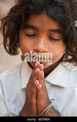 Young Indian street girl in prayer with folded hands Stock Photo