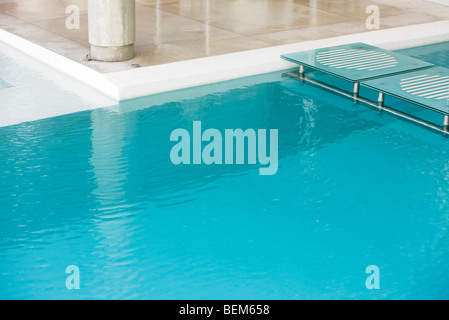 Stepping stones spanning deep end of swimming pool Stock Photo