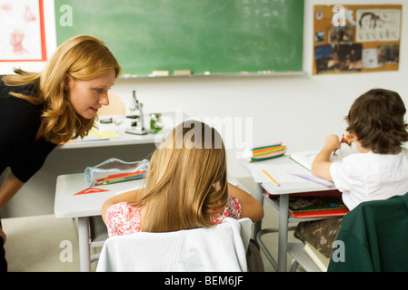 Teacher helping student in elementary classroom Stock Photo