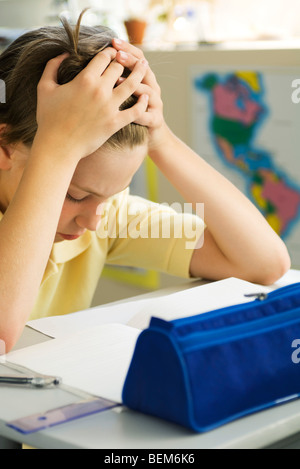 Boy sitting at desk with head in hands Stock Photo