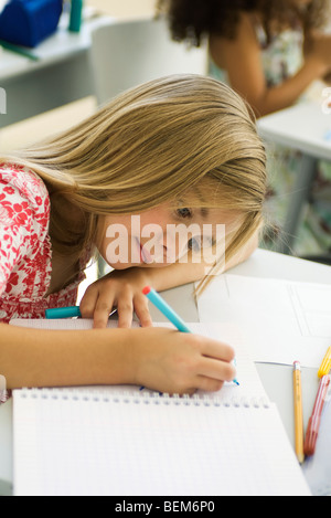 Girl resting head on arm, drawing in notebook Stock Photo