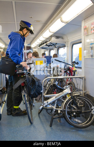 Side view of male commuter parking his bicycle in the rack on a Caltrain Bombardier train car. Stock Photo