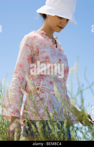 Young woman wearing sunhat, walking through tall grass Stock Photo