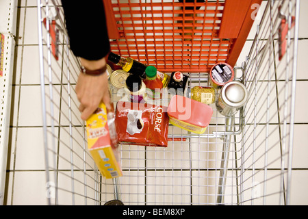 Shopper placing groceries in shopping cart Stock Photo