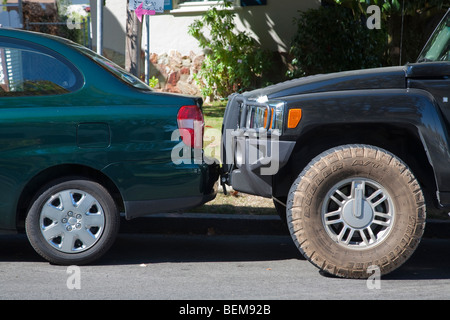 A H3 Hummer parked right up against the bumper of a Toyota Echo. Stock Photo