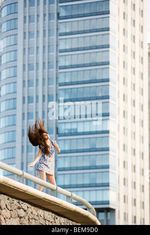 Young woman dancing on balcony, tossing hair Stock Photo