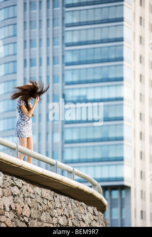 Young woman standing on balcony, tossing hair Stock Photo