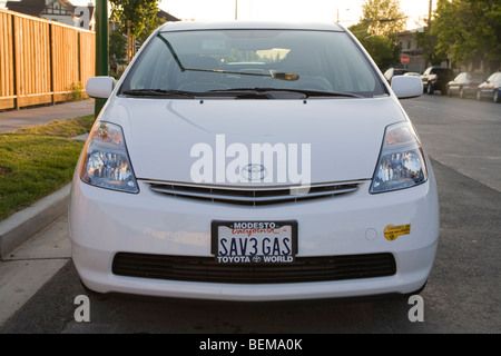 Front view of a white Toyota Prius with a 'SAV3 GAS' (Save Gas) license plate and a clean air vehicle sticker. Stock Photo