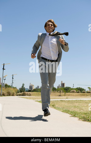 Businessman running down sidewalk with look of determination Stock Photo