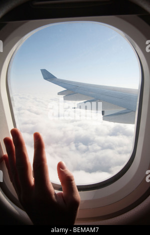 A passenger's hand on an airplane window. The airplane is Airbus A340, operated by Cathay Pacific airline. Stock Photo