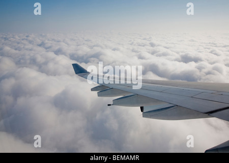 An airplane wing above clouds. The airplane is Airbus A340, operated by Cathay Pacific airline. Stock Photo