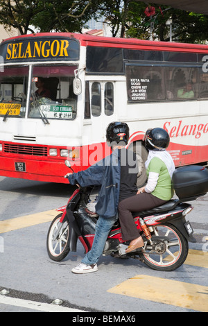 Two people on a moped giving way to a city bus in downtown Kuala Lumpur. Kuala Lumpur, Selangor, Malaysia Stock Photo