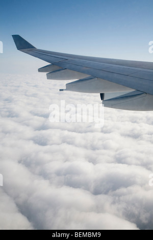 An airplane wing above clouds. The airplane is Airbus A340, operated by Cathay Pacific airline. Stock Photo