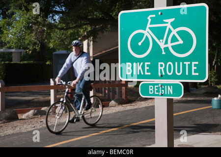 Bike route sign marks the path as a bicycle commuter exits the Stevens Creek Trail at the southern extension Stock Photo