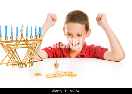 Cute little boy on Chanukah playing with his dreidel. Isolated on white with menorah and gelt.  Stock Photo