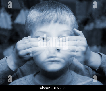 A small boy with eyes covered in an ethereal double exposure. Autism and blindness concepts Stock Photo