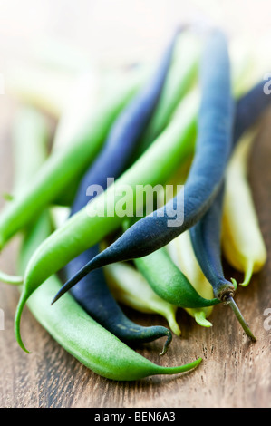 Pile of purple yellow and green string beans on cutting board Stock Photo