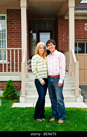 Young happy couple standing in front of house Stock Photo