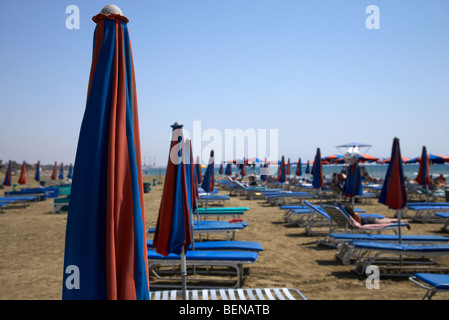 folded up umbrellas and empty sun loungers on cyprus tourist organisation municipal beach in larnaca bay republic of cyprus Stock Photo