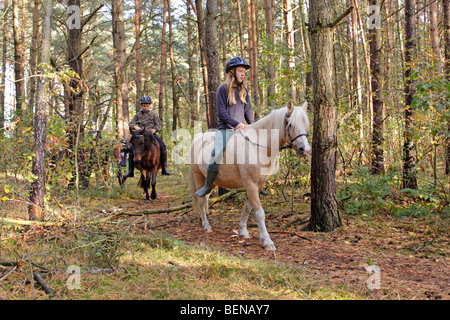 children riding on their ponies through a forest Stock Photo