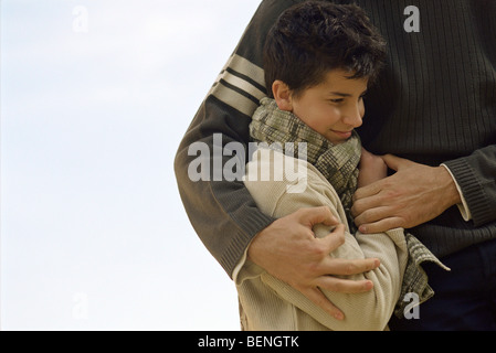 Boy being embraced by father, cropped Stock Photo