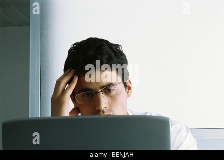 Man working on computer, holding head Stock Photo
