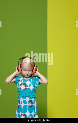 Little girl with eyes closed wearing protective headphones Stock Photo