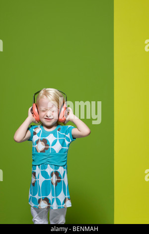 Little girl with eyes closed wearing protective headphones Stock Photo