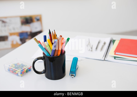 Markers, pens and pencils in mug on desk with school supplies Stock Photo