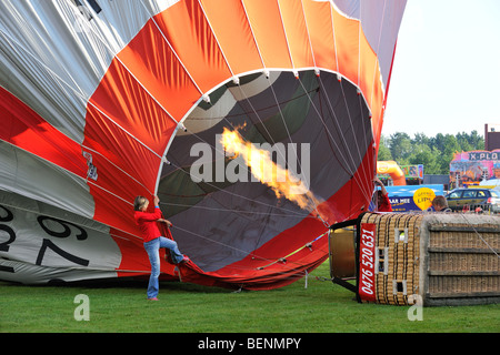 Balloonists / Aeronauts filling hot-air balloon with hot air from gas flame during ballooning meeting Stock Photo