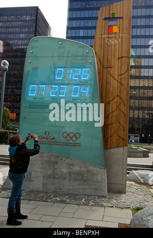 Woman tourist taking digital camera photo of Omega 2010 Winter Olympics countdown LED clock Vancouver BC downtown Stock Photo