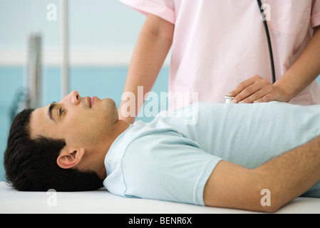 Nurse listening to man's chest with stethoscope, cropped Stock Photo