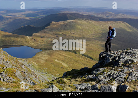A female hill walker admires the view from Aran Fawddwy in Snowdonia, North Wales. The lake of Creiglyn Dyfi lies below. Stock Photo