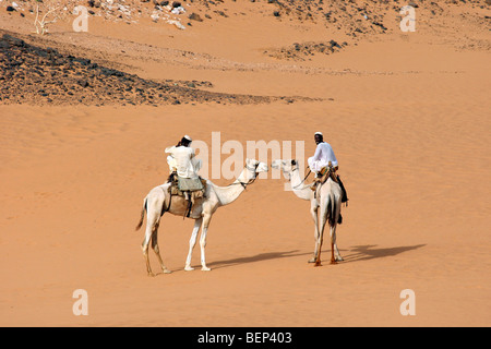 Two Nubian men dressed in thawbs riding dromedary camels (Camelus dromedarius) in the Nubian desert of Sudan, North Africa Stock Photo
