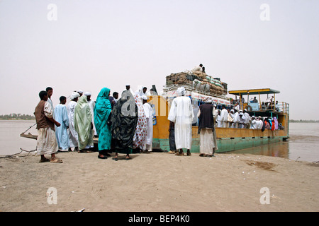 Nubian passengers dressed in thawbs / thobes / dishdashas boarding ferry boat over the river Nile, Sudan, North Africa Stock Photo