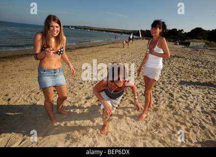 three women, a grandmother, her daughter and granddaughter playing on beautiful white sandy beach in the British Summer time Stock Photo