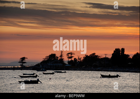 Sunset on Legoe Bay on Lummi Island, Washington. Reef net salmon fishing skiffs wait for the new day to resume the salmon catch. Stock Photo