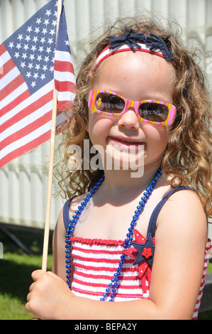 Young girl dressed in patriotic colors holds flag at parade Stock Photo