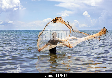 Fisherman fishing casting his net in Kep beach, South Cambodia Stock Photo