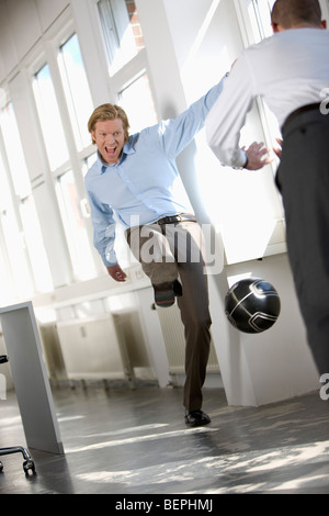 men are playing soccer in an office Stock Photo