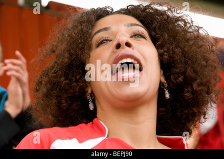 Female fan singing at football match