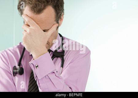 A doctor holding his hand over his face Stock Photo