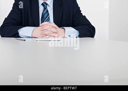 man sitting, hands clasped Stock Photo