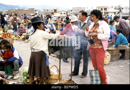 Woman roasting corn on small metal brazier in local upland Ecuador market. Stock Photo