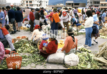 Group of women sit amongst vegetables for sale in local upland Ecuador market. Stock Photo