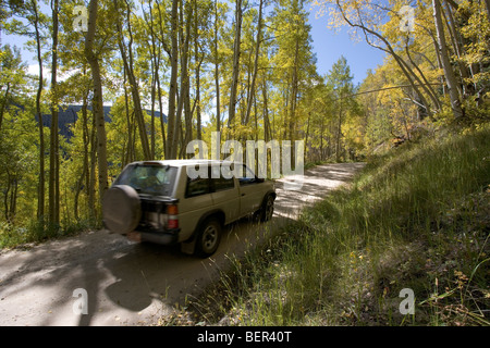 A 4 wheel drive SUV on a dirt road near Telluride, Colorado amongst the aspens which are turning color in late September. Stock Photo